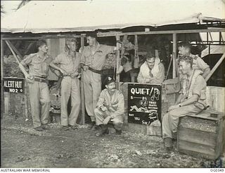 KIRIWINA, TROBRIAND ISLANDS, PAPUA. 1944-02-17. AT THE ALERT HUT NO. 2 OF NO. 76 (KITTYHAWK) SQUADRON RAAF, PILOTS AWAIT A CALL. FROM LEFT: SERGEANT (SGT) I. G. PEACOCK, HOBART, TAS; FLIGHT ..