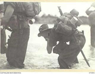 Members of the 35th Infantry Battalion pause for refreshment at the river during their advance up the coast towards Wewak. The soldier drinking water has conveniently positioned his cigarettes in ..