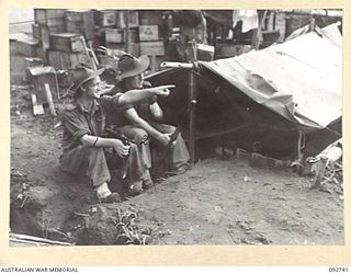 SORAKEN, BOUGAINVILLE. 1945-06-02. PRIVATE D.O. VINCENT (1) AND PRIVATE H.R. FOSTER (2), MEMBERS OF 2 MOUNTAIN BATTERY, OUTSIDE A TYPICAL GUNNERS DUGOUT WITHIN A FEW FEET OF THEIR GUNS SO THAT THEY ..
