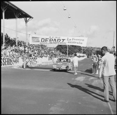 Spectators watching rally car no. 3 crossing the finish line during the 1st Safari Calédonien racing event, New Caledonia, 1967 / Michael Terry