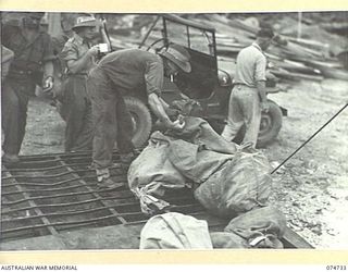 MADANG, NEW GUINEA. 1944. AUSTRALIAN TROOPS LOADING BAGS OF MAIL ABOARD THE 593RD UNITED STATES BARGE COMPANY'S COURIER BARGE. THIS COURIER SERVICE IS RUN BY THE AMERICAN UNIT FOR THE 5TH DIVISION