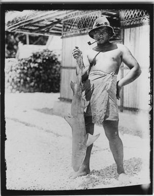 "Man brought hat and smokers beep holding 1 shark upside-down in the tail fin. The man stands in front of a building. Clothing. Clothes. : A series with a photon. 4352: 1-7. See also photon. photon 4349-4351. "