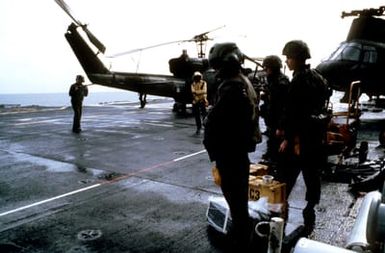 Near Granada. Flight operations take place aboard the amphibious assault ship USS GUAM (LPH 9) during Operation URGENT FURY. Visible in the background is the tail of a UH-1 Iroquois helicopter and the front of a CH-46 Sea Knight