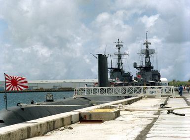 Starboard view of the Japanese submarine ARASHIO (SS 565) moored in Apra Harbor. The frigates JDS TOKACHI (DE 218), right, and JDS OOI (DE 214) can be seen to the right