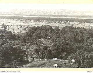 RAMU VALLEY, NEW GUINEA, 1944-02-29. THE VIEW OVERLOOKING KESAWAI. "D" COMPANY, HEADQUARTERS 2/12TH INFANTRY BATTALION CAN BE SEEN IN THE FOREGROUND. IN THE DISTANCE LIES THE RAMU VALLEY AND THE ..