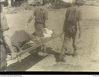 Dugumur Bay, New Guinea. 1944-06-14. Troops of the 4th Infantry Battalion carrying an Indian ex-prisoner-of-war by stretcher to an aircraft for transport to Madang for medical treatment. This man ..