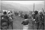 Pig festival, pig sacrifice, Tsembaga: men engage in trade exchanges, watched by women and children on edge of dance ground
