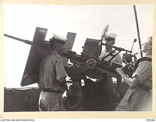 AT SEA, OFF BUIN, BOUGAINVILLE. 1945-08-20. AN OERLIKON GUN CREW AT ACTION STATIONS ON THE BRIDGE OF THE CORVETTE HMAS LITHGOW, AS JAPANESE BARGES ESCORTED BY THREE RAN MOTOR LAUNCHES APPROACH ..