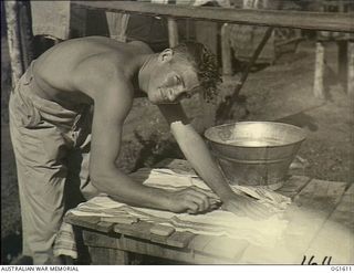 TADJI NEAR AITAPE, NORTH EAST NEW GUINEA. C. 1944-10. MEMBER OF NO. 100 (BEAUFORT) RAAF WITH A BASIN, SCRUBBING HIS LAUNDRY ON A TABLE