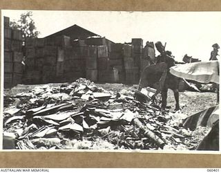 17 MILE, LALOKI RIVER, NEW GUINEA. 1943-11-22. LOOKING OVER A HEAP OF BROKEN BOTTLES TOWARDS A STACK OF EMPTY BOTTLES AT THE CORDIAL FACTORY ESTABLISHED AND OPERATED BY THE AUSTRALIAN DEFENCE ..