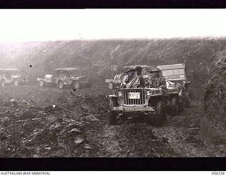 REINHOLD HIGHWAY, NEW GUINEA. 1943-08-23. CONVOY OF HEADQUARTERS, ROYAL AUSTRALIAN ENGINEERS, 11TH AUSTRALIAN DIVISION, ON THE NEWLY COMPLETED HIGHWAY AT THE ELOA BASIN. IN THE LEADING JEEP, ON THE ..