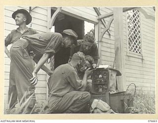 JACQUINOT BAY, NEW BRITAIN. 1944-11-04. SIGNALLERS OF THE 14/32ND INFANTRY BATTALION SETTING UP A WIRELESS POST AT THE FRONT DOOR OF THE MALMAL MISSION CHURCH TO ESTABLISH COMMUNICATION WITH THE ..