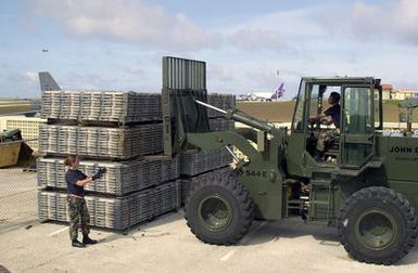 US Air Force (USAF) SENIOR AIRMAN (SRA) Amy Christopherson, from Elmendorf Air Force Base (AFB), directs STAFF Sergeant (SSGT) Allan Abistado, from Yokota Air Base (AB), Japan, as he drives a 10K All Terrain (AT) forklift and moves cargo pallets at Andersen Air Force Base (AFB), Guam