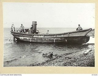 1942-10-01. NEW GUINEA. MILNE BAY. AUSTRALIAN SOLDIERS EXAMINE A BARGE USED IN THE UNSUCCESSFUL ATTACK ON MILNE BAY