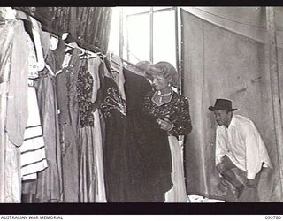TOROKINA, BOUGAINVILLE, 1945-11-03. PRIVATE G. J. BUCKHAM, FEMALE IMPERSONATOR, SELECTING A GOWN FOR THE NEXT ACT AND SERGEANT J. WILSON CHANGING COSTUME DURING THE SHOW STAGED FOR TROOPS BY ..