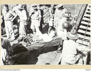 PORT MORESBY, PAPUA. 1942-08. AN AUSTRALIAN SOLDIER WOUNDED IN ACTION AGAINST THE JAPS IN NEW GUINEA BEING CARRIED ON TO THE HOSPITAL SHIP MANUNDA FOR EVACUATION TO AUSTRALIA