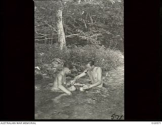 MILNE BAY, PAPUA. 1943-07-31. NAKED MEN, LEADING AIRCRAFTMAN (LAC) LAC K. W. GILL, SYDNEY, NSW (LEFT) AND LAC H. HARDIE, KOGARAH, NSW, WASHING A FILM IN A JUNGLE STREAM AFTER IT WAS DEVELOPED IN ..