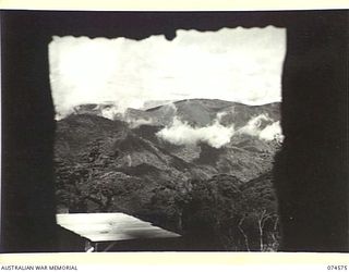 NEW GUINEA. 1944-07-09. A SECTION OF THE RUGGED MOUNTAIN COUNTRY THROUGH THE NEW WAU-BULLDOG ROAD PASSES VIEWED THROUGH THE WINDOW OF ONE OF THE HUTS AT SECOMBE CAMP