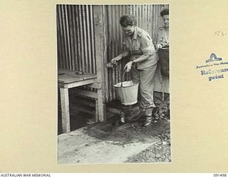 LAE, NEW GUINEA, 1945-05-07. CORPORAL E. ALLBURY (1) AND CORPORAL D.M. O'CONNELL (2), GETTING WATER TO WASH OUT THEIR NEW QUARTERS AT THE AUSTRALIAN WOMEN'S ARMY SERVICE BARRACKS, BUTIBUM ROAD. ..