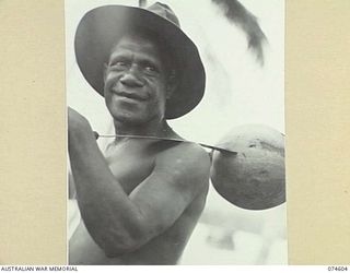 MALAMAL, NEW GUINEA. 1944-07-13. ORAU, A MADANG BOY, LOOKS PLEASED WITH HIS "DIGGER" HAT AND COCONUT AS HE RETURNS TO THE AUSTRALIAN NEW GUINEA ADMINISTRATIVE UNIT NATIVE LABOUR COMPOUND AT THE ..