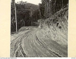 WAMPIT, NEW GUINEA, 1944-03-01. THIS BROAD HIGHWAY SIXTY THREE AND THREE-QUARTER MILES FROM WAU ON THE WAU - LAE ROAD SECTION ILLUSTRATES THE CAPABILITIES OF AN ANGLEDOZER. THE ROAD IS IN AN ..