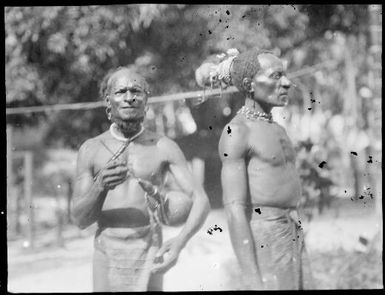 Ramu Delta man wearing a cuscus fur headdress and another man standing beside, Awar, Sepik River, New Guinea, 1935 / Sarah Chinnery