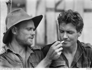 AITAPE AREA, NEW GUINEA. 1945-02-13. NX122980 CAPTAIN A.J. MARSHALL, 2/2ND INFANTRY BATTALION AND OFFICER- IN- CHARGE, "JOCK FORCE" LIGHTS A CIGARETTE FOR VX53309. WARRANT OFFICER II, G.W. EDWARDS, ..