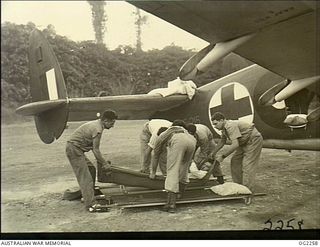 TOROKINA, BOUGAINVILLE ISLAND, SOLOMON ISLANDS. C. 1945-02-18. ARMY PATIENT BEING TRANSFERRED TO A STRETCHER PRIOR TO BEING LOADED ON AN AMBULANCE AIRCRAFT OF NO. 37 (TRANSPORT) SQUADRON RAAF AT ..