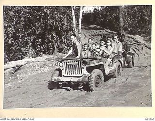 BOUGAINVILLE, 1945-07-13. A JEEP AND TRAILER LOADED WITH SIGNALLERS FROM 3 DIVISION SIGNALS AND NATIVE CARRIERS NEGOTIATING A MUDDY SECTION OF THE BUIN ROAD BETWEEN THE OGORATA RIVER AND THE MOBIAI ..