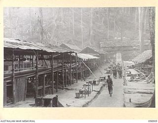 MASAMASA ISLAND, SOLOMON ISLANDS. 1945-11-14. AN INSPECTION PARTY WALKING ALONG THE MAIN PATH OF JAPANESE AREA 13, OPERATIONS, SHOWING HUTS ON BOTH SIDES. JAPANESE CONCENTRATED ON THE ISLAND ARE ..