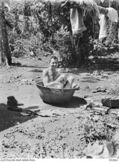 NANTAMBU, NEW BRITAIN. 1945-06. LIEUTENANT R.H. LUKE, 2/2 FORESTRY COMPANY, TAKES A BATH IN A DISCARDED JAPANESE RICE BOWL WHILE A HOSPITAL PATIENT AT 2/4 FIELD AMBULANCE