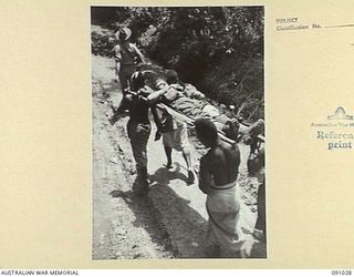 BOUGAINVILLE. 1945-04-17. NATIVES CARRY A 24 INFANTRY BATTALION BATTLE CASUALTY ALONG BUIN ROAD DURING ACTION AT HATAI JUNCTION