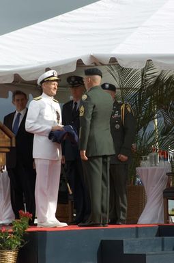 Outgoing Commander-in-CHIEF US Pacific Command Admiral Dennis C. Blair receives his Four-Star flag as he relinquishes command during the Change of Command Ceremony for the Commander-in-CHIEF US Pacific Command at Marine Corps Base, Kaneohe Bay, Hawaii. During the Ceremony Admiral Dennis C. Blair relinquished his command to Admiral Thomas B. Fargo. General Richard B. Myers, USAF, Chairman of the Joint Chiefs of STAFF, and Deputy Secretary of Defense, The Honorable Paul E. Wolfowitz are on the podium in the background