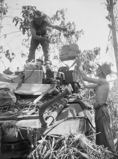 BOUGAINVILLE. 1945-04-16. TROOPER W.F. HOLE (1), AND TROOPER T.L. CUSOCK (2), MEMBERS OF B SQUADRON, 2/4 ARMOURED REGIMENT, UNLOADING GEAR FROM THE BACK OF THEIR MATILDA TANK AFTER THEY HAD MOVED ..