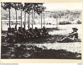 YALU, NEW GUINEA. 1945-08-03. SERGEANT HILLGROVE, NEW GUINEA TRAINING SCHOOL, INSTRUCTING STUDENTS IN THE USE OF THE PROJECTILE INFANTRY TANK ATTACK GUN