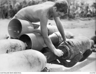 AITAPE, NORTH EAST NEW GUINEA. C. 1945-06. LEADING AIRCRAFTMAN LES DONNELLY OF QLD, ARMOURER, ADJUSTING FUSING UNIT OF A 500LB BOMB FOR DELIVERY BY RAAF BEAUFORT BOMBER AIRCRAFT ON TADJI AIRFIELD ..