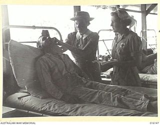 NEW GUINEA. 1943-11-17. MEMBERS OF THE AUSTRALIAN ARMY MEDICAL WOMEN'S SERVICE (AAMWS) AT AN AUSTRALIAN FIELD HOSPITAL, SISTER IRVINE AND PRIVATE (PTE) D. EASTLE ADMINISTER EYE DROPS TO PTE. R.C. ..
