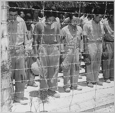 Japanese Prisoners of War at Guam, with bowed heads after hearing Emperor Hirohito make announcement of Japan's unconditional surrender.