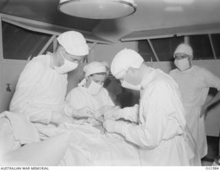 MADANG, NEW GUINEA. C. 1945-01. "MEN IN WHITE". SPOTLESSLY CLEAN AND 100% STERILE OPERATING THEATRES IN RAAF HOSPITALS ARE EQUIPPED TO UNDERTAKE ALL TYPES OF MAJOR SURGICAL OPERATIONS. PERFORMING ..