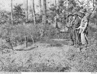 KAIAPIT, NEW GUINEA, 1943-09-22. MEMBERS OF THE 2/6TH AUSTRALIAN INDEPENDENT COMPANY AT THE GRAVES OF THEIR COMRADES WHO WERE KILLED DURING THE RAID ON KAIAPIT. LEFT TO RIGHT:- QX25652 PRIVATE L.J. ..