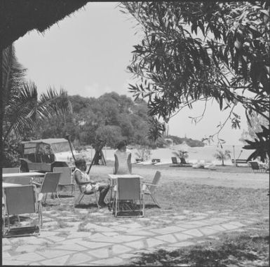 Two woman at picnic area with beach and a jeep in the background, Isle of Pines, New Caledonia, 1967 / Michael Terry