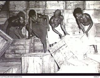 LAE, NEW GUINEA, 1946-01-11. NATIVES STACKING CASES OF BEER IN THE STORE AT AUSTRALIAN ARMY CANTEENS SERVICE BULK STORES