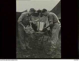 New Guinea. 1 April 1944. RAAF members flying Liberator aircraft at camp. Flight Sergeant A. C. Scott of Deepdene, Vic, is pouring water from a canvas bucket, as Sergeant E. M. Atkinson of ..