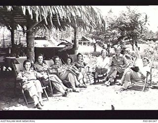 MADANG. 1945. MEMBERS OF THE AUSTRALIAN ARMY NURSING SERVICE, 2/11TH AUSTRALIAN GENERAL HOSPITAL, RELAXING IN CANVAS DECK CHAIRS OUTSIDE THE MESS HUT