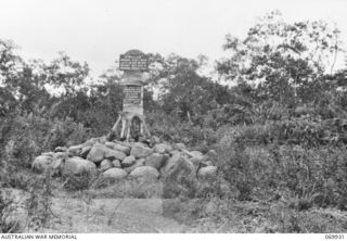 MILNE BAY, NEW GUINEA. 1943-01. A MEMORIAL SET UP ON THE EDGE OF NO. 3 AIRSTRIP (TURNBULL FIELD) CONSISTING OF A COCONUT PALM STUMP WITH ROCKS PILED AROUND THE BASE. AFFIXED TO THE MEMORIAL IS A ..