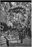 Bride price ritual: man holds large payment banner of feather and shell valuables, marsupial skins