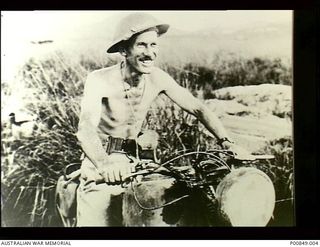 Near Port Moresby, New Guinea. Portrait of 252288 Flight Lieutenant Stuart H. Collie RAAF who was an intelligence officer with No. 75 Squadron at Port Moresby, sitting bare-chested on his motorbike ..