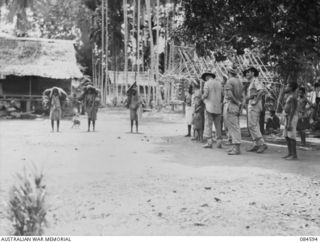 BUKAWA, HUON GULF, NEW GUINEA. 1944-12-14. THE VILLAGE SCENE AS 43 LANDING CRAFT COMPANY MEMBERS TALK AND TRADE WITH NATIVES FOR SOUVENIRS. SEVERAL JAPANESE WATER BOTTLES AND COOKING UTENSILS WERE ..