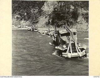 WAMPIT, NEW GUINEA, 1944-03-02. A SUPPLY CONVOY BEING TOWED ACROSS THE RIVER AT WAMPIT BY A FERRY TRUCK FROM HEADQUARTERS, COMMANDER ROYAL ENGINEERS (A.I.F.). THE TOWING TRUCK SAVES REMOVING ..