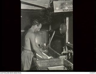 MILNE BAY, PAPUA. 1943-07-31. LEADING AIRCRAFTMAN M. MORTON OF MELBOURNE, VIC, DEVELOPING PRINTS IN A DARKROOM FROM FILM EXPOSED DURING AN OPERATIONAL MISSION BY A P38 LOCKHEED LIGHTNING ..